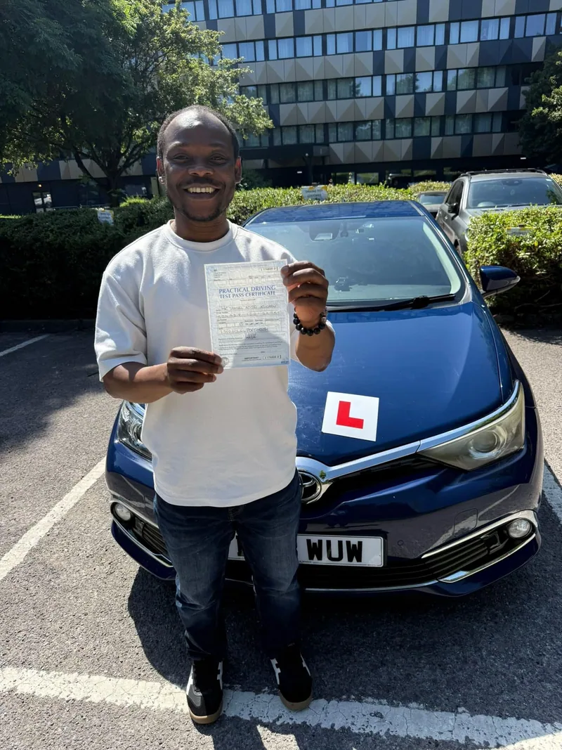 A DWP Driving School pupil holding up a test pass certificate beside DWP Driving School's navy learner car