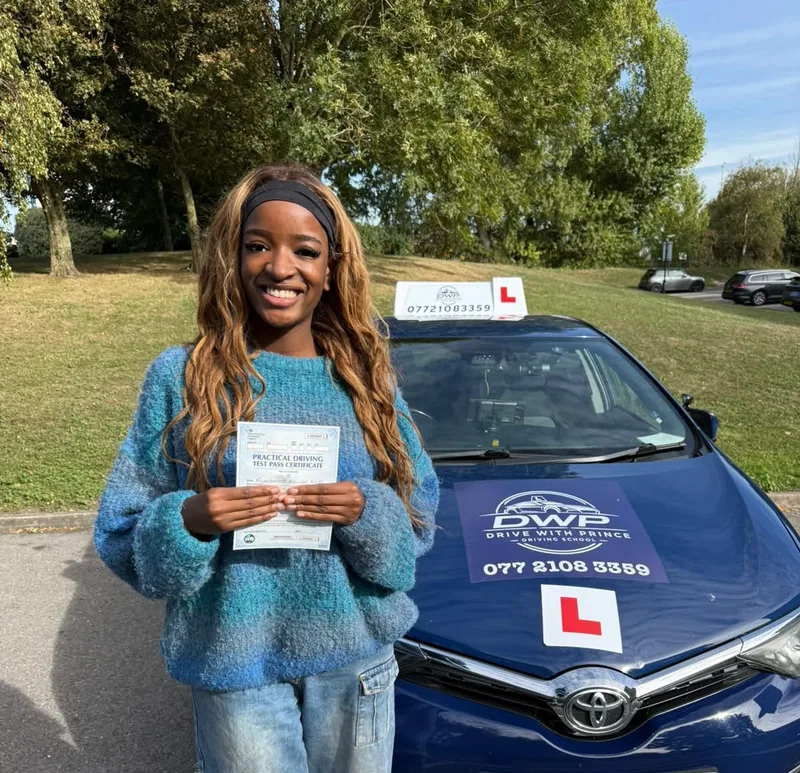 A DWP Driving School pupil holding a test pass certificate in front of DWP Driving School's navy learner car